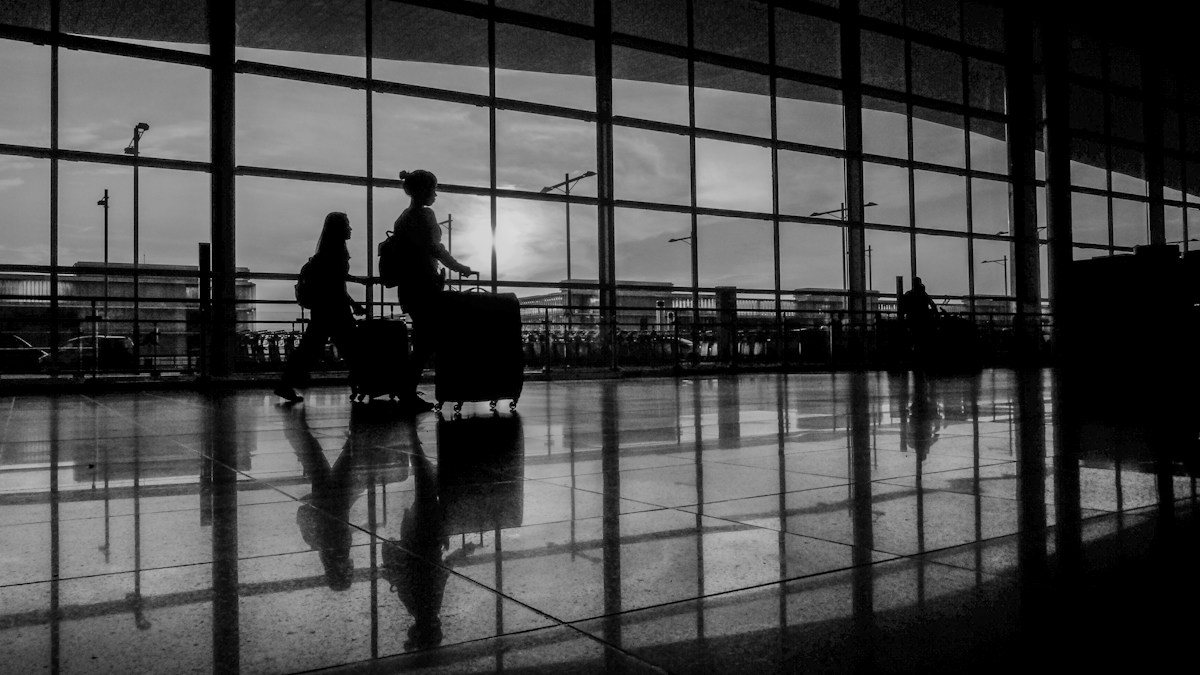 Travellers with luggage at Barcelona El Prat Airport.