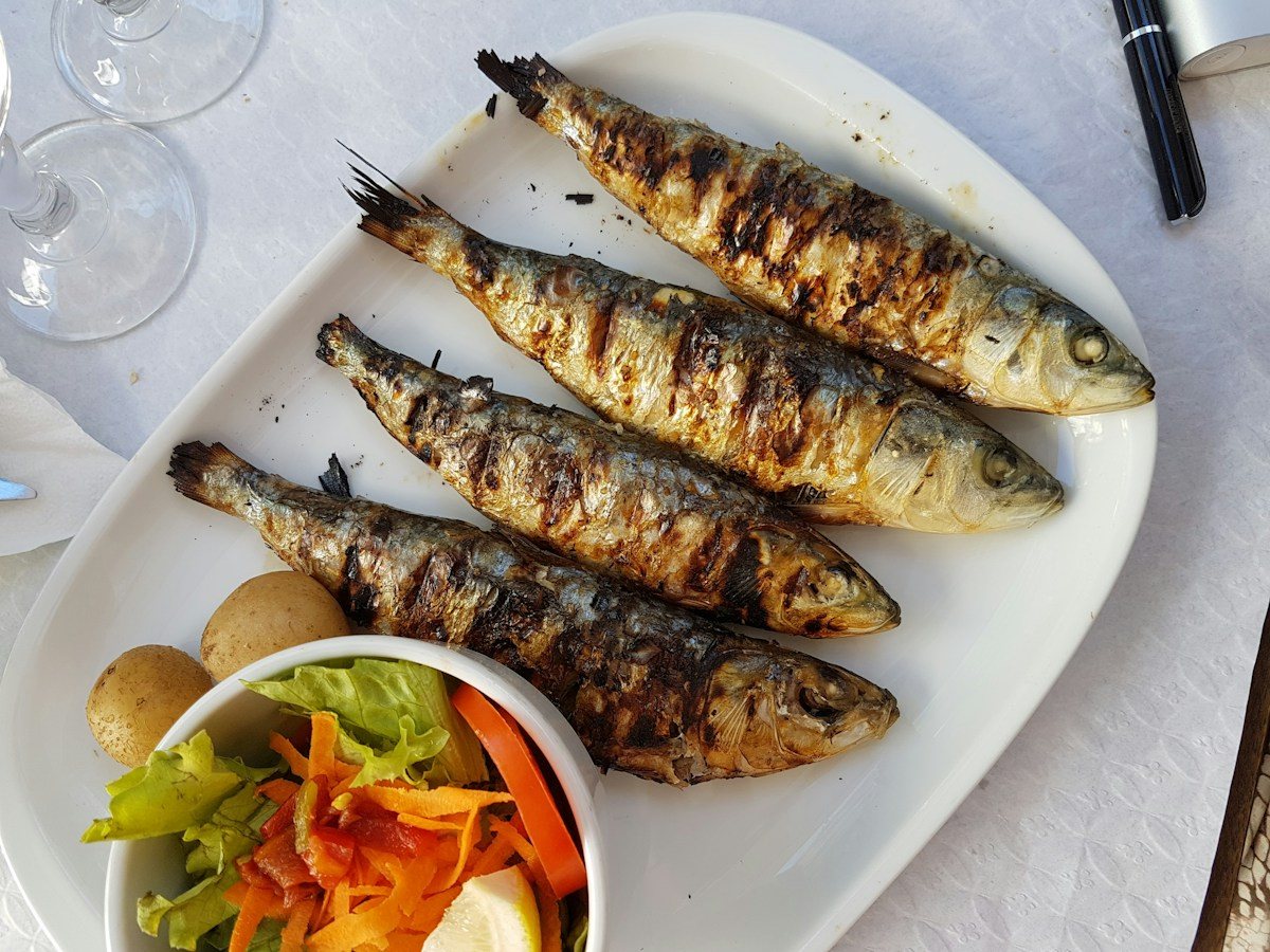 Grilled sardines served with vegetables, photographed in Lisbon.