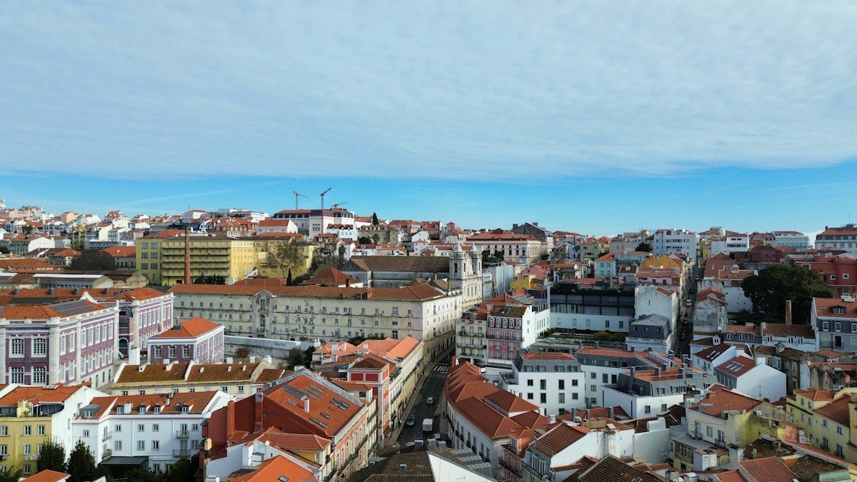 Aerial view across Lisbon rooftops toward the Tagus River.
